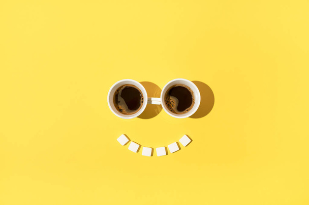 Relaks poranna kawa czas z oczami wykonane z dwóch filiżanek kawy i uśmiech wykonane z kostek cukru. - Zdjęcie, obraz