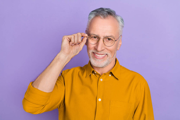 Photo of smart elder white hairdo man hand eyewear wear yellow shirt isolated on purple color background - Fotó, kép