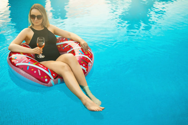 Femme avec verre rouge de vin relaxant dans la piscine. - Photo, image