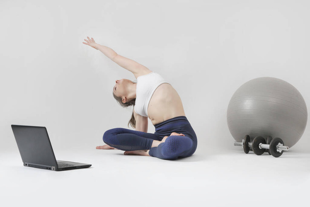 Serie of photos of young fit woman practising yoga in front of laptop. Studio shot on white background. - Foto, imagen