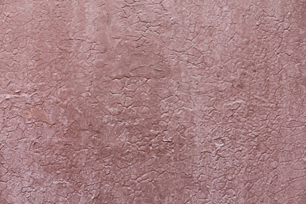 Red concrete wall background with detailed texture. A painted plaster surface with cracks and damages. - Fotografie, Obrázek