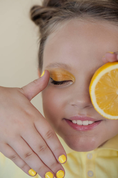 charming tween girl with slices of ripe lemon on yellow background. juicy fruit concept. summer. - Fotoğraf, Görsel