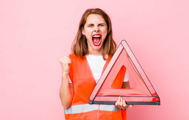 young pretty woman  shouting aggressively with an angry expression. car triangle emergency concept - Foto, Bild