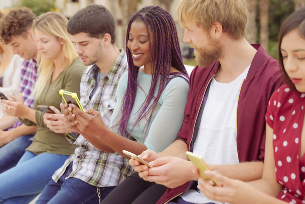 Gruppo di amici che guardano telefoni cellulari intelligenti. Adolescenti dipendenti dalle nuove tendenze tecnologiche. Concetto di gioventù, tecnologia, sociale e amicizia. - Foto, immagini