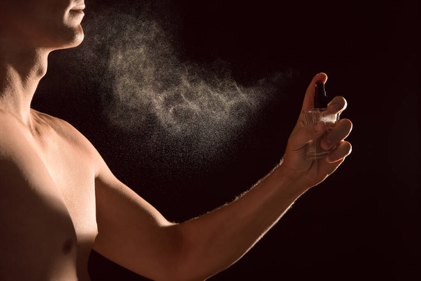 Young man applying perfume on black background, closeup - Foto, Bild