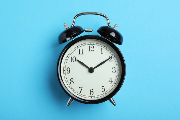 Alarm clock on light blue background, top view. School time - 写真・画像