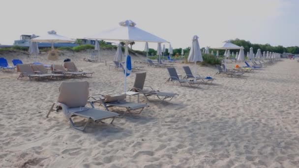 Hermosa vista de la playa de arena vacía con tumbonas y sombrillas contra el telón de fondo del mar en el día de verano. Países Bajos. - Imágenes, Vídeo