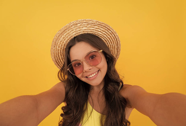 glücklich Teenager Mädchen im Sommer Strohhut und Brille Selfie machen auf gelbem Hintergrund, Kindheit - Foto, Bild
