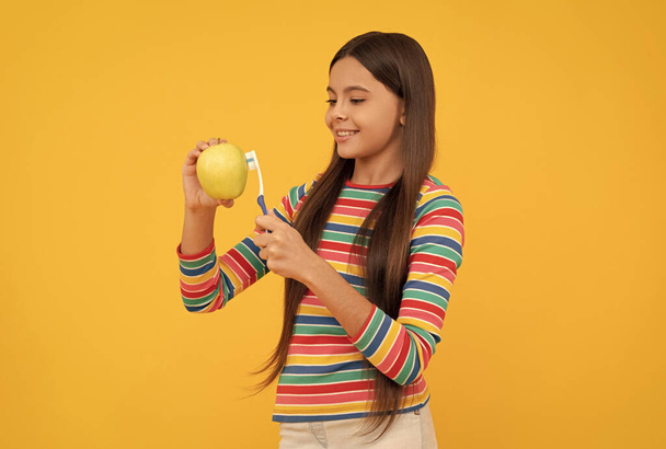 Auffrischen. Glückliches Kind putzt Apfel mit Zahnbürste. Zahnpflege. Vitamine für gesunde starke Zähne - Foto, Bild