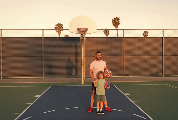 счастливые папа и сын ребенок играют в баскетбол с мячом на детской площадке, родительские права - Фото, изображение
