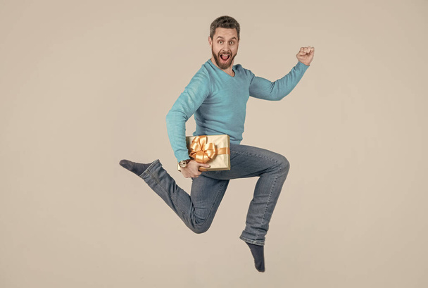 jumping handsome man with present box. businessman giving birthday gift. energetic unshaven man - Photo, Image