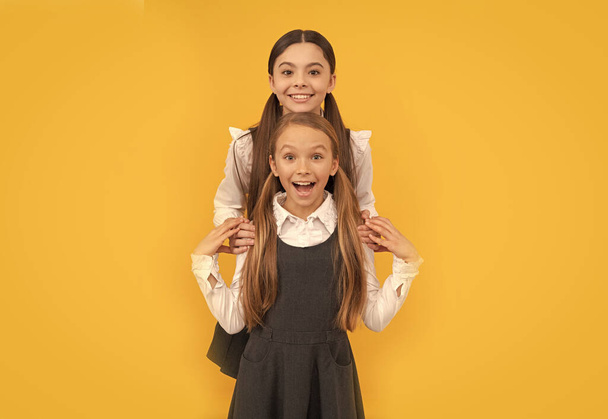 Glückliche Schulfreunde umarmen sich in formellen Uniformen gelben Hintergrund, Freundschaft - Foto, Bild