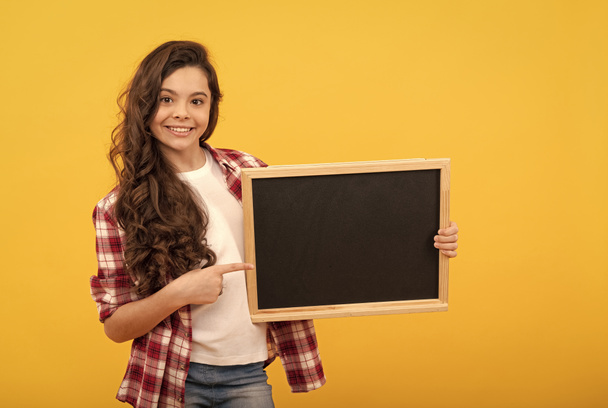 happy kid pointing finger on school blackboard for copy space, education - Photo, Image