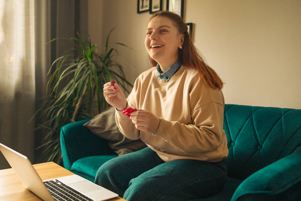 freelance mains femme avec écouteurs sans fil rouge rester à la maison assis canapé confortable salon intérieur - Photo, image