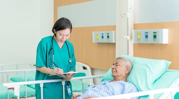 Azjatycka pielęgniarka zajmująca się starszym azjatyckim mężczyzną i mówiąca o jego zdrowiu w szpitalu., Koncepcja medyczna i zdrowotna. - Zdjęcie, obraz