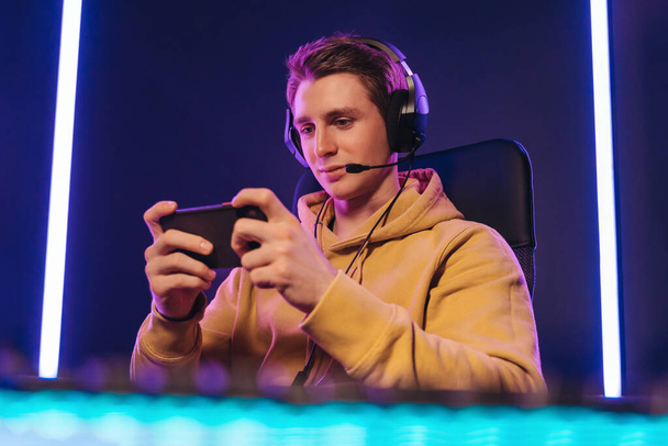Pro cyber sportsman playing in mobile video game at home - Foto, afbeelding