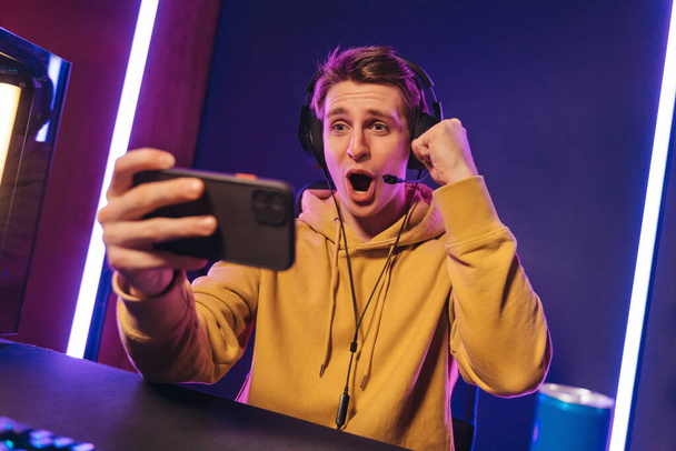 Pro gamer με ακουστικά εξόδου με τη νίκη σε απευθείας σύνδεση παιχνίδι για κινητά - Φωτογραφία, εικόνα