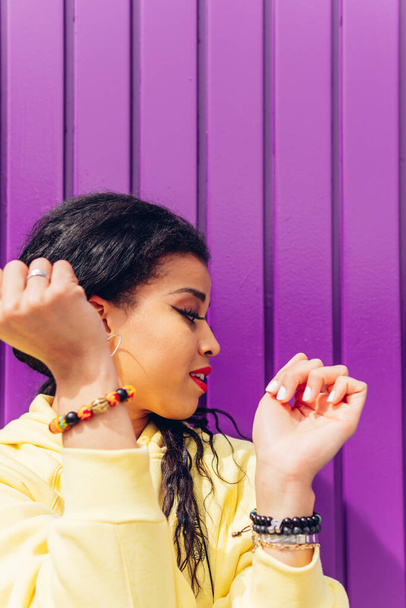Portrait of the face of a young trap dancer, with yellow clothes and a purple background. African girl dancing relaxed current music outdoors. - Photo, Image