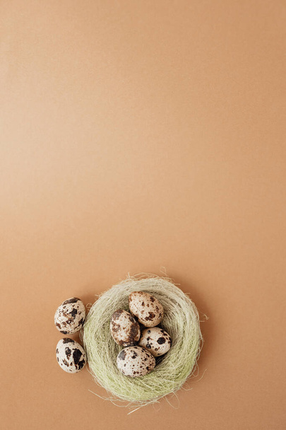 Quail eggs in a sisal nest on a pastel beige background. Easter decoration, egg minimalist design, modern design template, copy space, top view. - Fotoğraf, Görsel