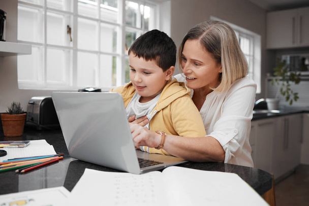 Laten we inloggen voor wat werk. Foto van een moeder en zoon team met behulp van een laptop om thuis onderwijs te voltooien. - Foto, afbeelding