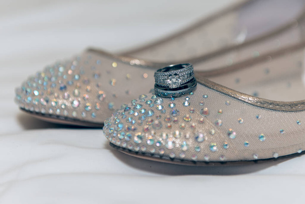 Wedding ring of the bride and groom are neatly stacked on top of her shoes for the marriage ceremony. - Zdjęcie, obraz
