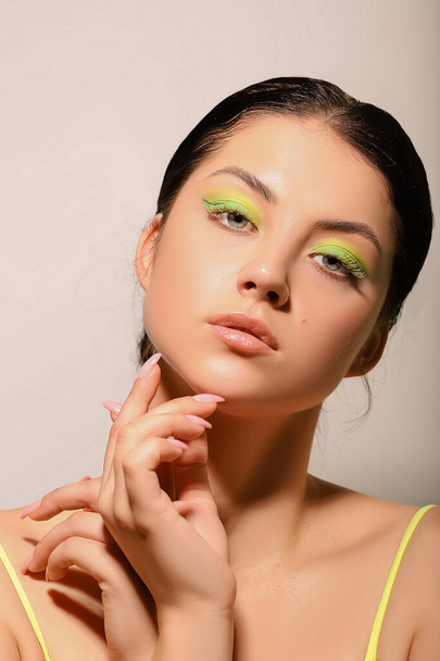 A girl with beautiful creative makeup touches her face with her hands - Foto, Imagen