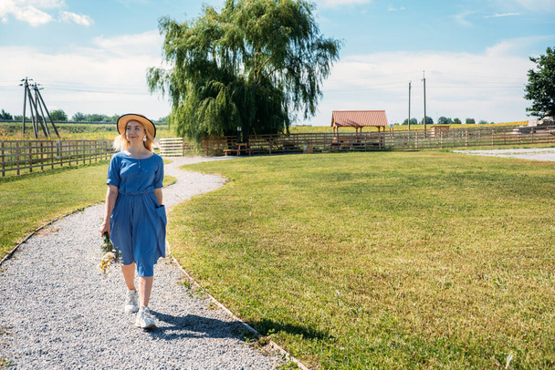 Cottages at Summer Village, Vacation Rentals. Domestic Travel, Local Travel, Summer Country Travel. Countryside Getaways. Young woman in straw hat enjoys summer vacation at the farm - Fotografie, Obrázek