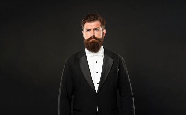 serious man in tuxedo bow tie looking forward. gentleman in formalwear on black background. - Foto, Imagen