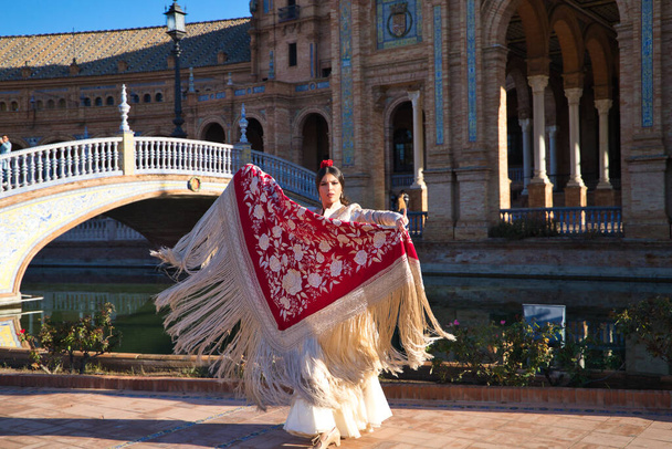 Flamenco-Tänzerin, Frau, Brünette und schöne typisch spanische Tänzerin tanzt mit einem roten Manila-Schal auf einem Platz in Sevilla. Flamenco-Konzept des kulturellen Erbes der Menschheit. - Foto, Bild