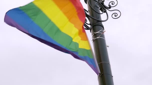 Φωτεινή σημαία ΛΟΑΤ προσδεδεμένη σε μαύρο πόλο κυματίζει στον άνεμο - Πλάνα, βίντεο