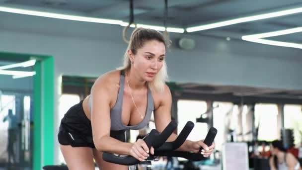 CrossFit Sarışın kadın egzersiz yapıyor kaslarını geriyor spor yapıyor Bisiklet eğitmeni sürüyor - Video, Çekim