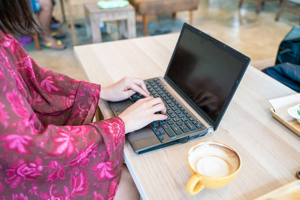 İş dünyasından güzel kadınlar, kafeteryada otururken dizüstü bilgisayar kullanırlar. - Fotoğraf, Görsel