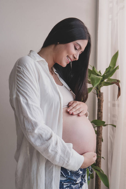 Schwangere Mutter hält ihren Bauch mit den Händen und spürt die Tritte der Babys - Foto, Bild