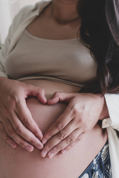 Mutter schwangere Frau macht ein Herz mit seiner Hand auf dem Bauch - Foto, Bild