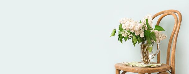 Vase with bouquet of beautiful white lilac on chair against light background with space for text - Photo, Image