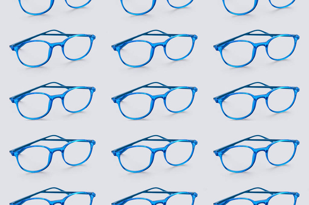 Stylish eyeglasses on light blue background. Pattern for design - 写真・画像