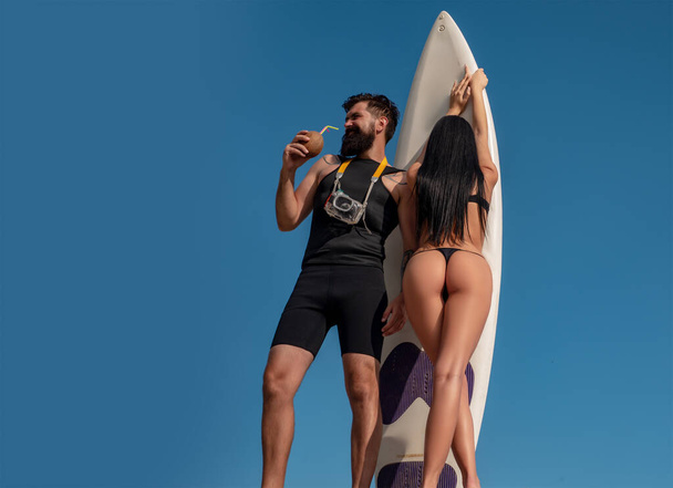 Щаслива пара серфінгу з дошкою для серфінгу розважається на пляжі. Спортивні сексуальні люди. Концепція способу життя у спортивних та молодіжних стосунках. Літній відпочинок. Молода сексуальна пара в літній день
. - Фото, зображення