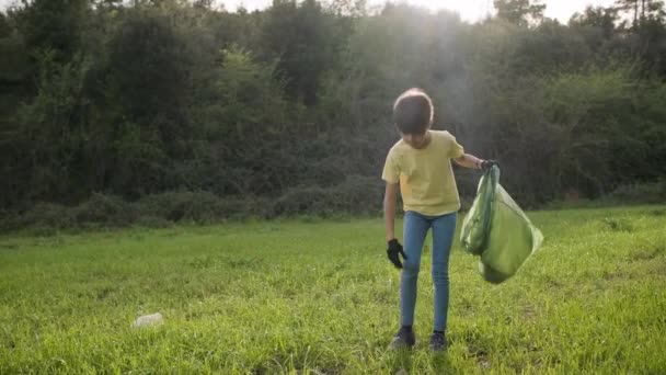 Young girl and her mother picking up garbage into trash plastic bag while cleaning up nature. - 映像、動画