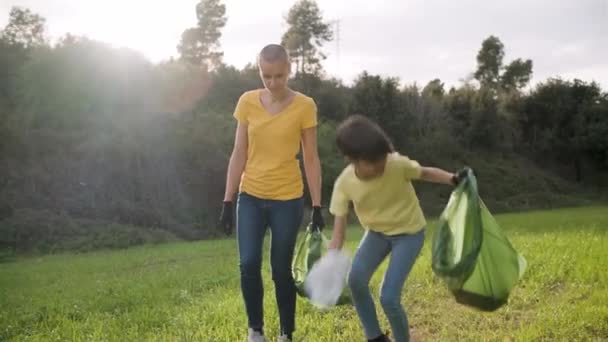Mother and daughter collecting garbage together to keep nature clean. - 映像、動画