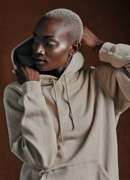 Her soul is fierce, her heart is brave, her mind is strong. Studio shot of an attractive young woman wearing a hoodie and posing against a brown background. - Zdjęcie, obraz