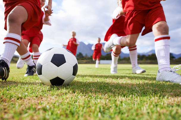 Running the game. Shot of a childrens soccer team on the field. - Φωτογραφία, εικόνα