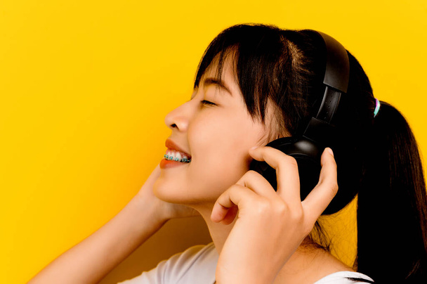 woman listening to music A young Asian woman in a white dress smiles happily. happy people lifestyle concept copy space mockup listen to music with headphones - Photo, Image