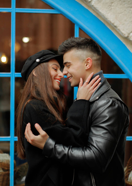 The couple in love in the rain - a beautiful girl hugs her boyfriend on a background of blue windows - 写真・画像