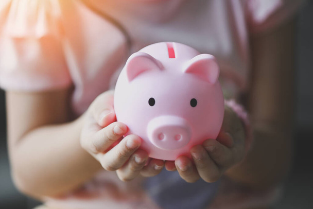 Child woman hand hold pink piggy bank for saving money for education study or investment , Save money concept, daughter hands holding pink piggy bank  - Foto, Imagen