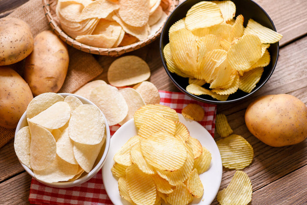 Batatas fritas lanche na tigela e prato, batatas fritas na mesa da cozinha e batatas cruas frescas no fundo de madeira - Foto, Imagem