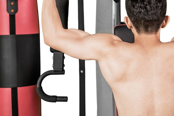 Rear view of muscle man exercising with weight lift machine while standing in the studio. Isolated on white background - Φωτογραφία, εικόνα