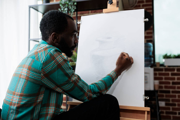 Αφρο-Αμερικανός καλλιτέχνης σχέδιο βάζο μοντέλο σε λευκό καμβά - Φωτογραφία, εικόνα