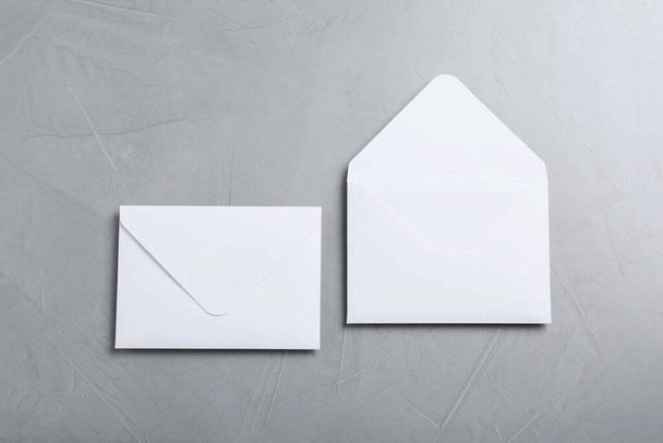 薄い灰色のテーブルの上にシンプルな白い紙の封筒、フラットレイ - 写真・画像