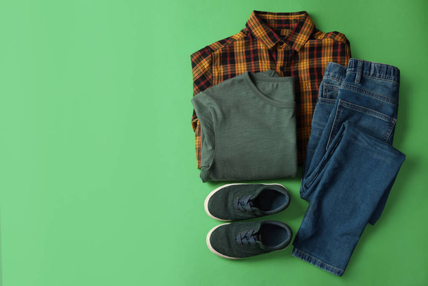 Stylish child clothes and shoes on green background, flat lay. Space for text - Foto, immagini
