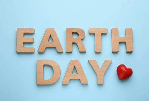 Phrase Earth Day made with wooden letters and red heart on light blue background, flat lay - Foto, Bild
